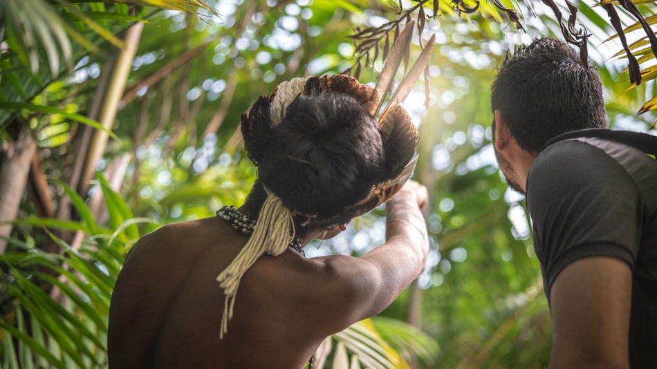 Indígena mostrando un detalle de la selva a un cooperante