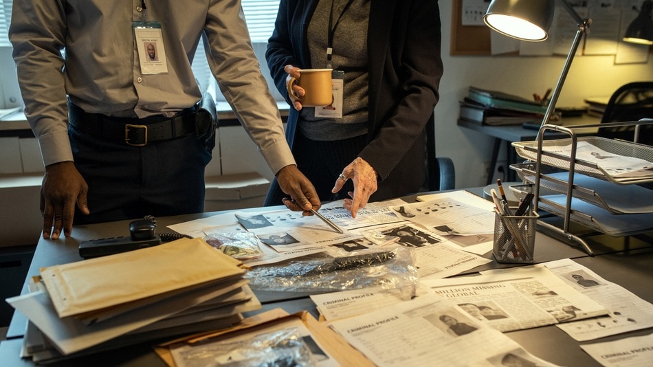 Detective de homicidios mirando información en la mesa de su despacho