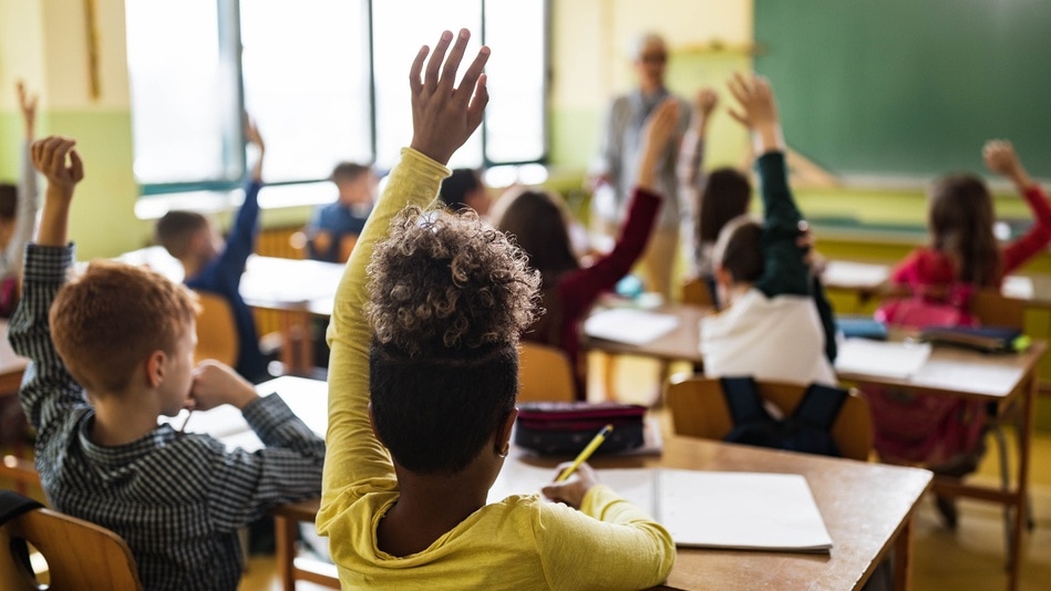Niños de clase de primaria con la mano levantada para pedir hablar